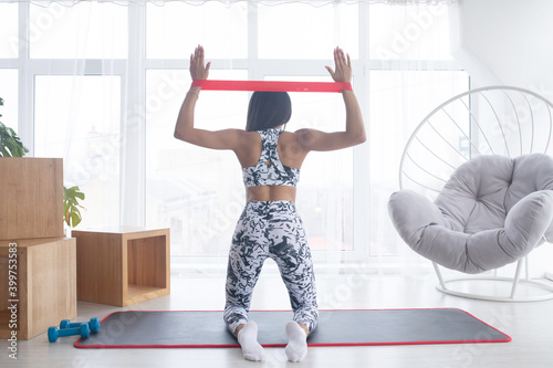 Woman during her fitness workout at home with rubber resistance band.