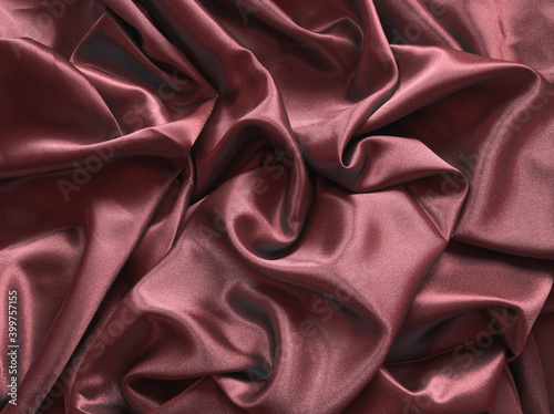 Elegant smooth claret satin, silk fabric drapes. Luxurious cloth textile with liquid wave. Abstract background or template. Fabric shiny glitter  texture. Luxurious wine color background.