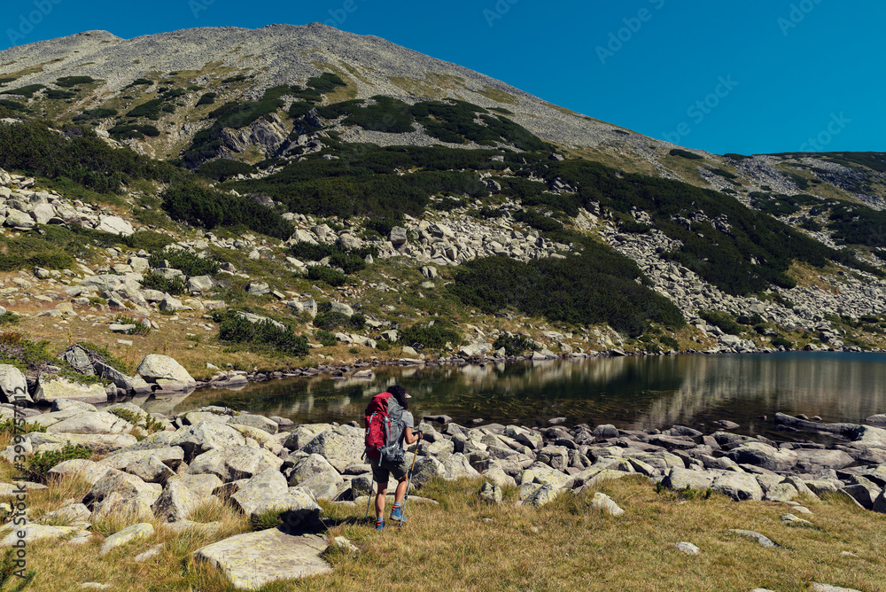 Woman looking at view of The Frog lake in Pirin mountain Selective focus