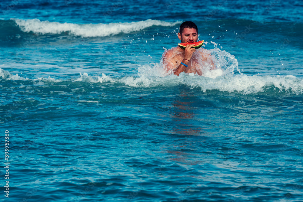 Caucasian man eating piece of watermelon in the sea water Selective focus