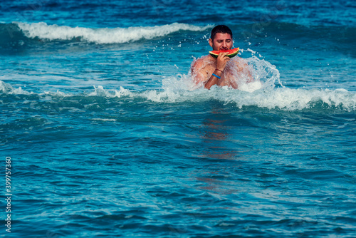 Caucasian man eating piece of watermelon in the sea water Selective focus © payamona