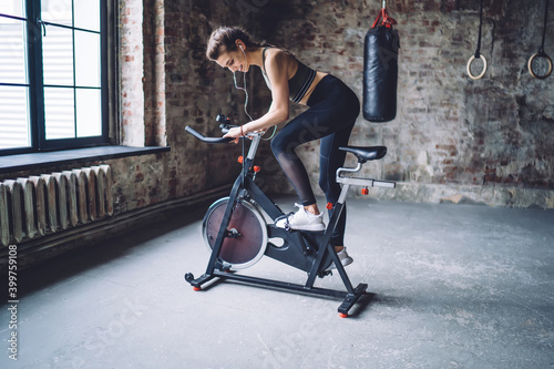 Cheerful sportswoman exercising on stationary bike photo