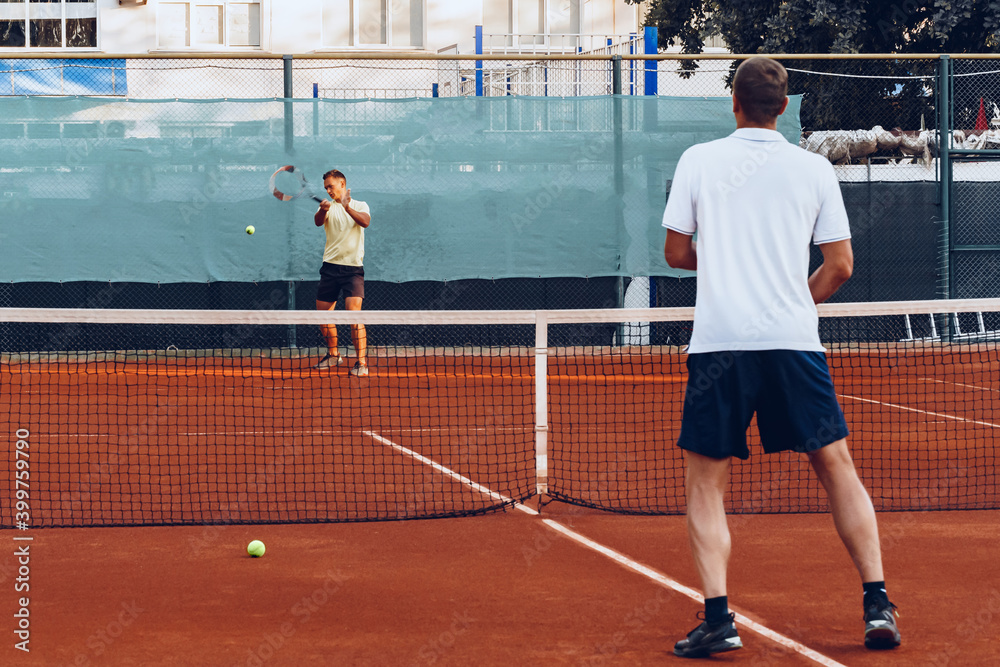 Two men playing tennis on clay tennis field