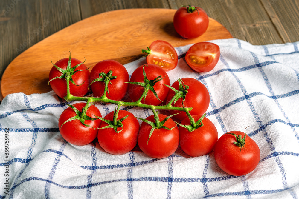 Cherry tomatoes on a branch on a wooden board and on a kitchen towel Cherry tomatoes on a branch on a wooden board and on a kitchen towel