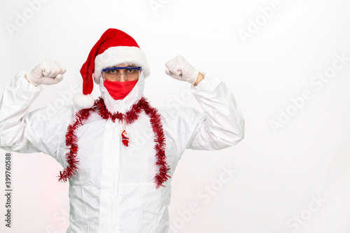 Health worker wearing protective clothing. He wears a santa hat on his head. He has a red corona mask on his face. © Alaka Film