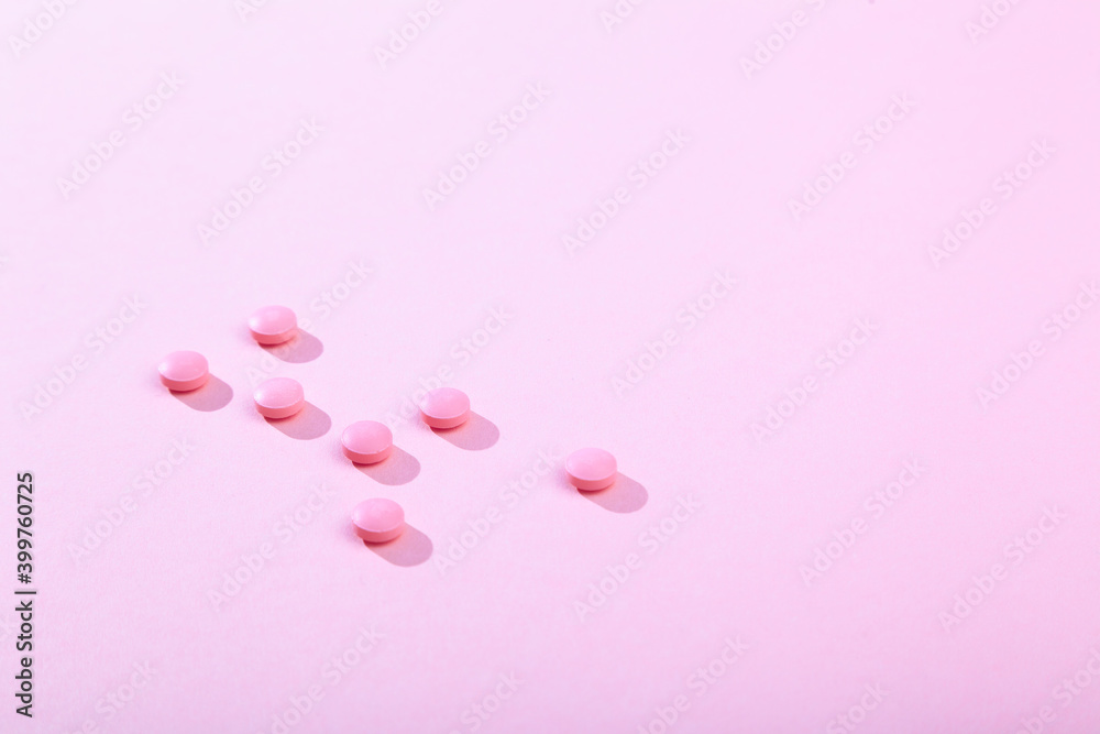 Tablets and pills, vitamins and antibiotic on pink background, copy space