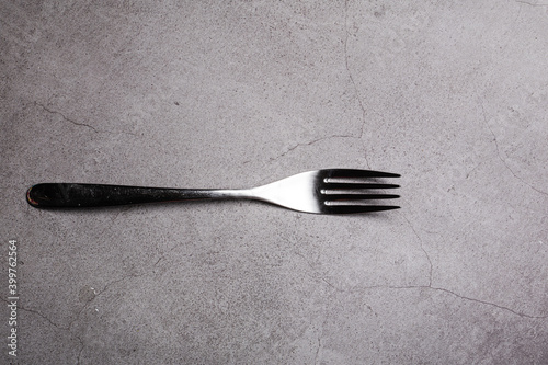 Bright Silver colored fork cutlery isolated on a grey background photo