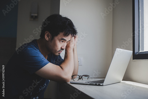 sad depression serious people from work stress concept.asian man feeling tired suffering using computer working work place.concept global economic and health problems