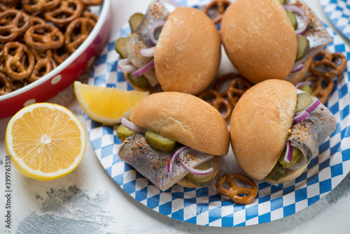 Close-up of german traditional fish sandwiches with herring fillet, pickles and red onion on a blue and white carton plate, studio shot photo