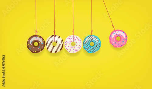 Newton's cradle from doughnuts. Collision balls made from donuts. Harm of sugar, donuts time or healthy diet concept. Dependence on flavoring, diabetes problems, weight loss.