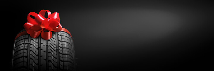 a  black isolation rubber tire, on the grey backgrounds in a bow for christmas