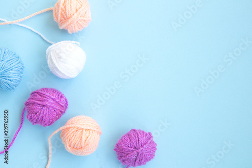 Several colorful skeins of thread on a light blue background with copy space