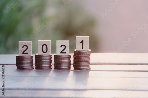 Coins stacks and Text of 2021 number written on wooden blocks with nature sunset background, Business and Saving money for new life new year concept, Selective focus.