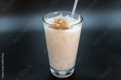 White horchata sweet drink sprinkled with sweetness and served in a clear glass with straw to quench your thirst.
