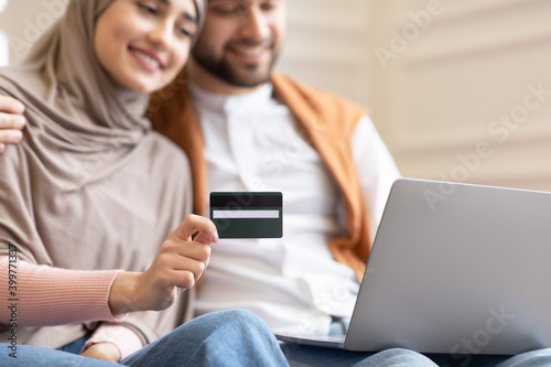 Online Shopping. Muslim Couple Using Credit Card And Laptop Indoor