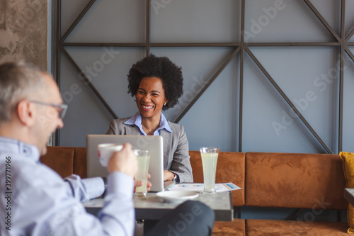 Happy African American businesswoman and her colleague having a casual meeting in a cafe.