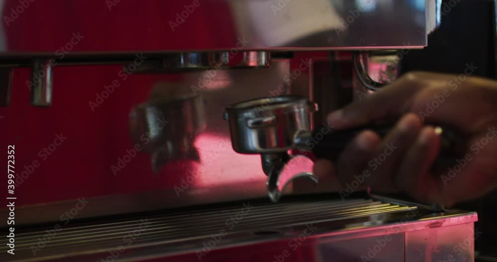 Midsection of african american male barista making coffee in coffee machine
