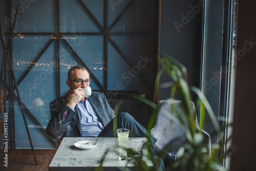 Photos Mid adult businessman spending his break in a cafe.