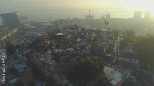 Sunrise aerial orbiting hilltop favela in Rio de Janeiro, Brazil with port and sea visible in the background photo