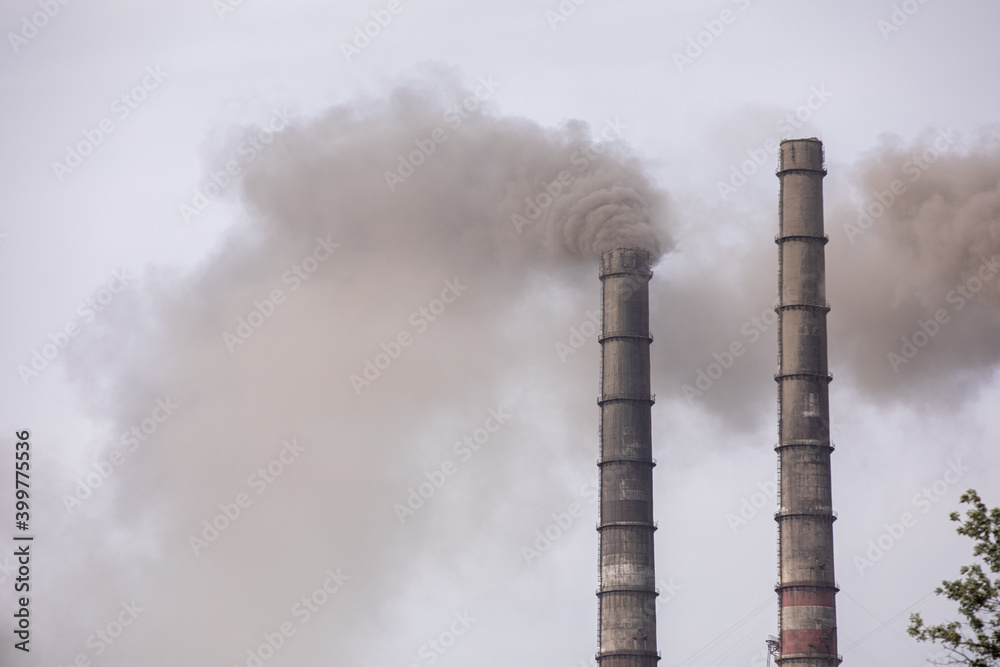 Smoke from two industrial chimneys, pipes, against the sky. Global warming. Air pollution. Ecological pollution. Air emissions polluting the city. Industrial waste is hazardous to health.