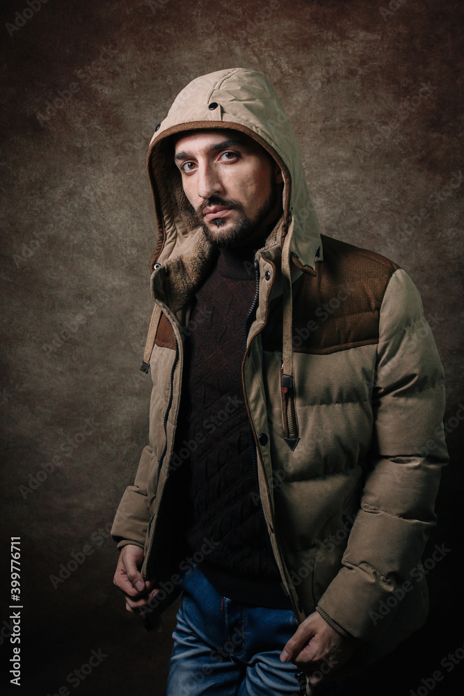 Portrait of a man. A man in a winter jacket. Winter fashion. Portrait on a brown background