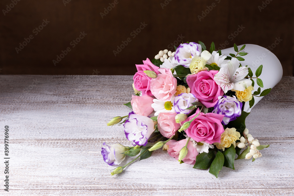 bouquet of roses, daisies, lisianthus, chrysanthemums, unopened buds in a white round box on a wooden table. bouquet of roses, daisies, lisianthus, chrysanthemums, unopened buds in a white round box on a wooden table.