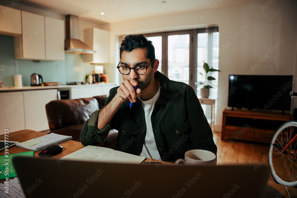 Mixed race business man wearing spectacles studying off desktop computer attending online meetings Mixed race business man wearing spectacles studying off desktop computer attending online meetings