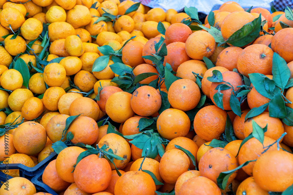 A group of citrus fruits including oranges and tangerines for sale at an outdoor market.