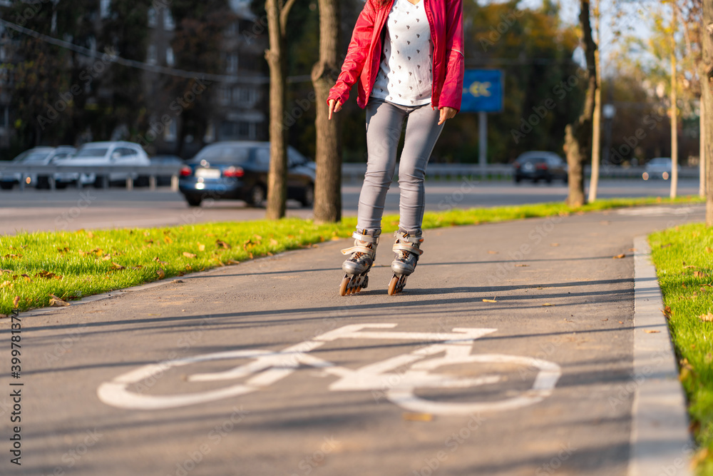 Active leisure. A sportive girl is rollerblading in an autumn park