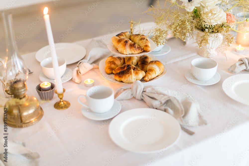 Christmas decoration of the festive table with cakes, glasses and candles