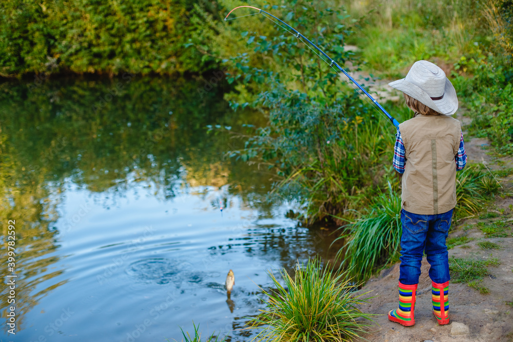 Child is fishing. Boy is a fisherman. Child with a fishing rod caught a fish in a pond. Nice catch! Child is fishing. Boy is a fisherman. Child with a fishing rod caught a fish in a pond. Nice catch!