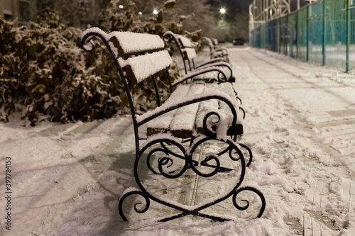 Lonely snow-covered benches under the evening lights