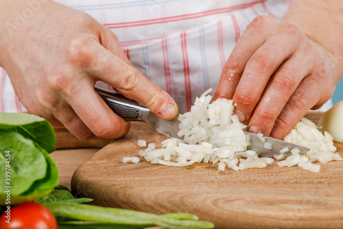 man cuts a white onion with a knife. The concept of cooking