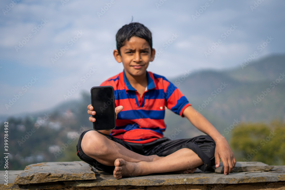 Young indian kid showing a mobile phone with black screen.