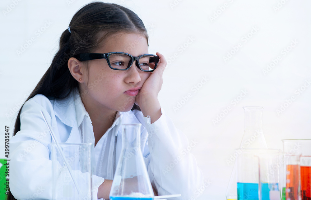 Stressed child girl in a lab coat is thinking about her experiments in chemistry class, education concept Stressed child girl in a lab coat is thinking about her experiments in chemistry class, education concept