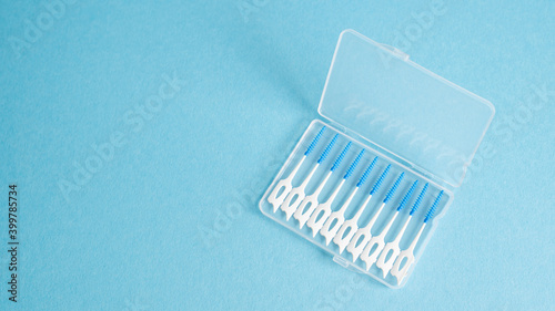 Top vie of interdental brush in portable case on blue background. Small brush for teeth. Home dental hygiene