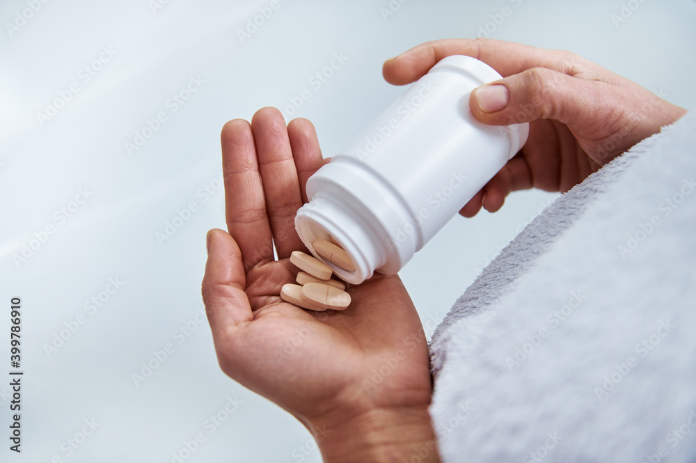Pouring the pills from the white bottle into the plam. Medicine and health care concept. Pouring the pills from the white bottle into the plam. Medicine and health care concept.