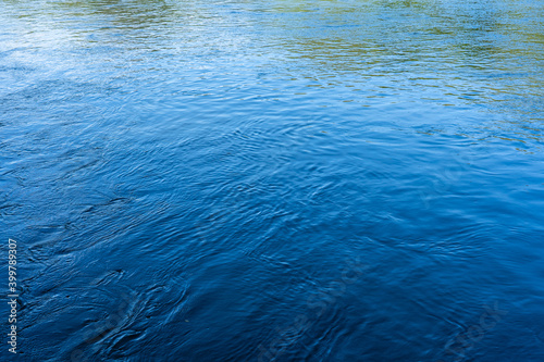 The clear stream flowing in the river reflects the blue sky with background.
