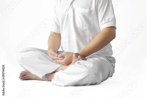 A man in a white robe meditating against a white backdrop with a clipping path.