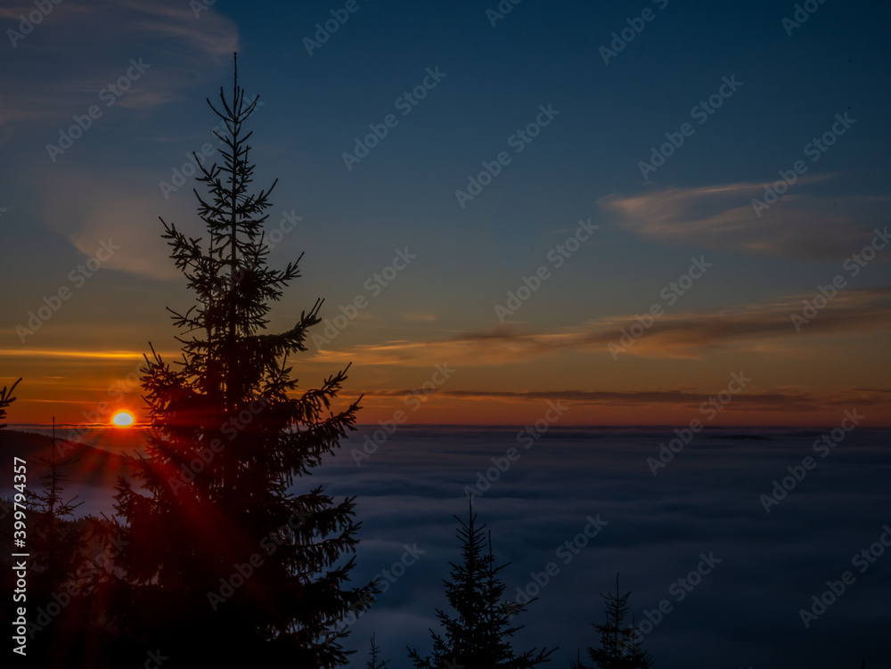 View from mountain range to the valley above fog and clouds at sunset