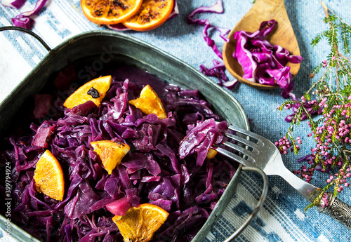 herbstgemüse rotkohl in einer schüssel, zubereitet mit zwiebeln und orangen, daneben ein zweig heidekraut