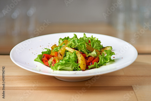 Roasted yellow and red bell pepper salad with capers and olives in a blue bowl.