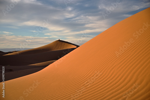 Textur von Bergen von Sand in der Abendsonne mit einer Person auf einem entfernten Berg von Sand