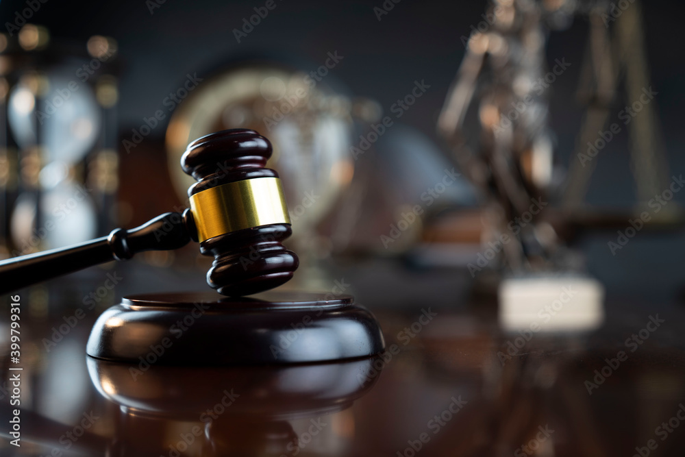 Law symbols composition. Judge’s gavel, Themis statue, scale, hourglass and old clock on the shining wooden brown table and the gray background. Law symbols composition. Judge’s gavel, Themis statue, scale, hourglass and old clock on the shining wooden brown table and the gray background.
