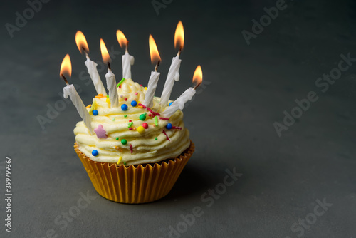 Birthday cupcake with many burning candles. Buttercream frosting, Sugar Confetti Sprinkles