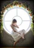 A woman in a white dress 35-45years old sits in a round window. She looks away.