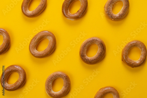 Freshly baked bagels on yellow background, top view. Creative pattern of bagels. Breakfast menu concept.