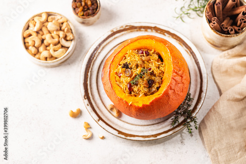 Tasty baked pumpkin stuffed with rice, vegetables, cashews and dried fruits on white background, top view