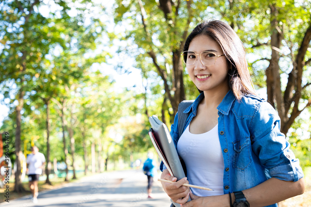 Beautiful asian woman holding diary with notebook and bright smile face in public park. She learning and work hard in the last weekend. Spring season tone Beautiful asian woman holding diary with notebook and bright smile face in public park. She learning and work hard in the last weekend. Spring season tone