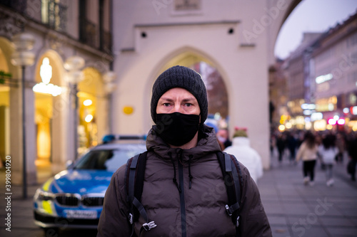 Mann mit Maske in München / mit Polizeiauto im Hintergrund - Corona Lockdown photo